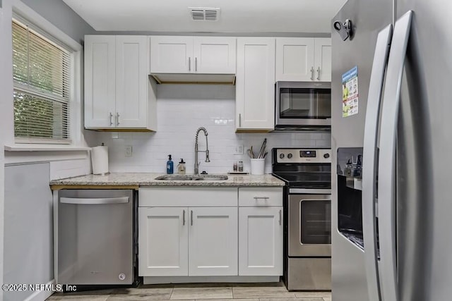 2969 Green St, Jacksonville, FL 32205 - kitchen featuring white cabinetry, visible vents, light stone counters, a sink, and stainless steel appliances