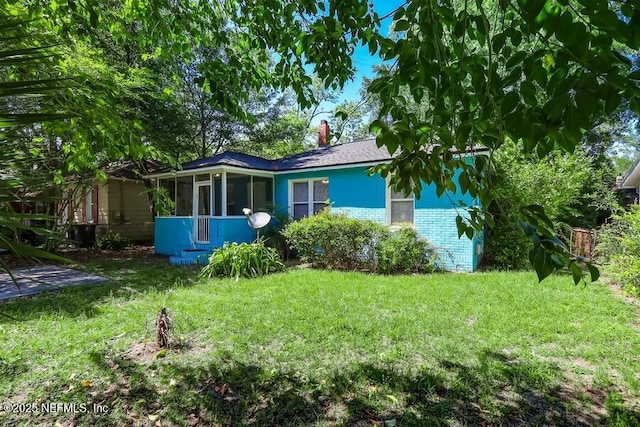 2969 Green St, Jacksonville, FL 32205 - view of side of home with an attached garage, a chimney, a sunroom, and a lawn