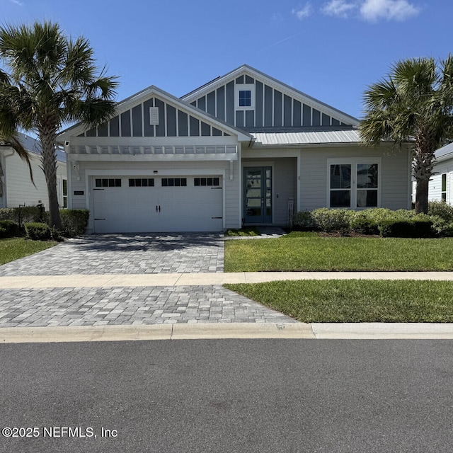 273 Caribbean Pl, Saint Johns, FL 32259 - view of front of property featuring a front yard, an attached garage, decorative driveway, french doors, and board and batten siding