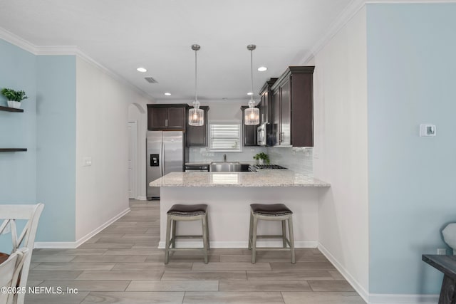 58 Strobe Ct, Saint Augustine, FL 32095 - kitchen with stainless steel appliances, dark brown cabinetry, crown molding, a peninsula, and a kitchen breakfast bar