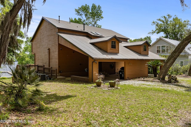 back of property featuring a lawn and metal roof