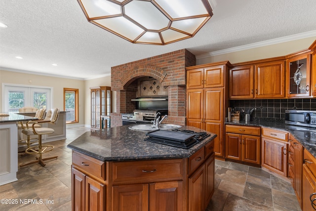 kitchen featuring glass insert cabinets, a textured ceiling, and brown cabinets