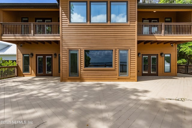 rear view of house with a wooden deck, french doors, and a balcony