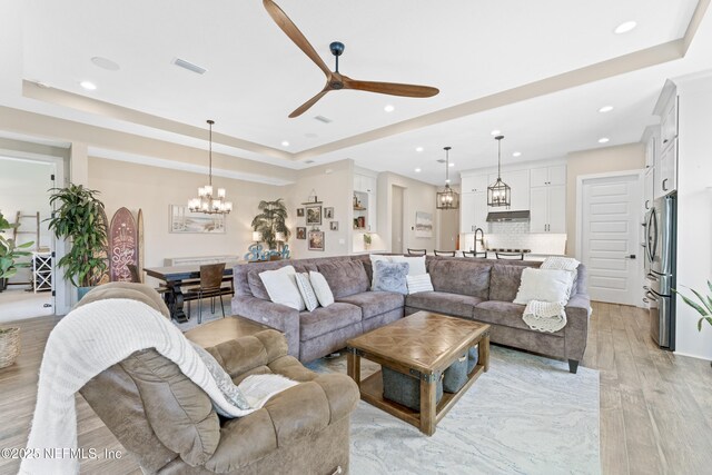 380 Maralinda Dr, Saint Augustine, FL 32095 - living room with recessed lighting, visible vents, a raised ceiling, light wood finished floors, and ceiling fan with notable chandelier