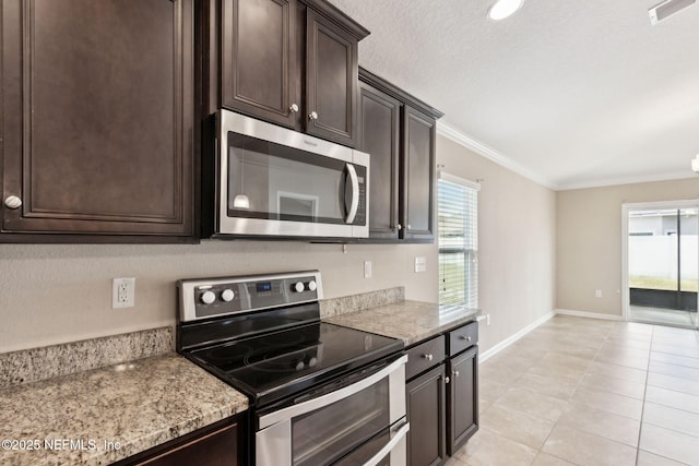 95210 Leafcrest Ct, Fernandina Beach, FL 32034 - kitchen with stainless steel appliances, light tile patterned flooring, dark brown cabinets, baseboards, and ornamental molding