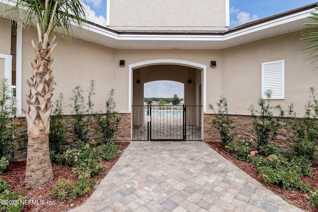 95210 Leafcrest Ct, Fernandina Beach, FL 32034 - view of exterior entry featuring stone siding, a gate, and stucco siding