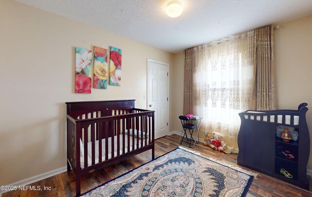 8413 Free Ave, Jacksonville, FL 32211 - bedroom with a crib, baseboards, a textured ceiling, and wood finished floors