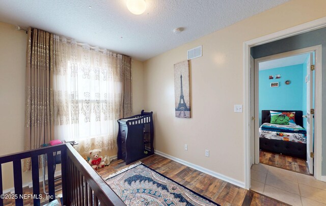 8413 Free Ave, Jacksonville, FL 32211 - bedroom with visible vents, baseboards, a textured ceiling, and wood finished floors