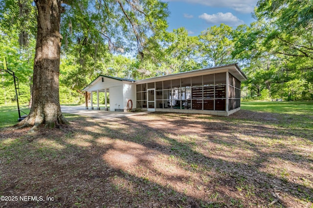 back of property with a sunroom and a lawn