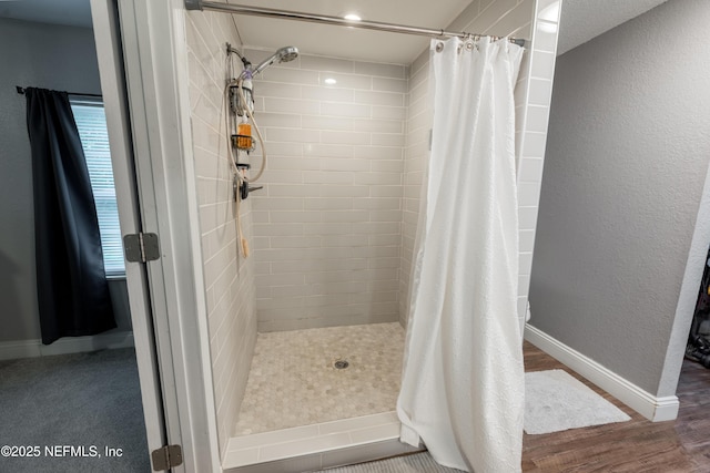 full bathroom with a shower stall, wood finished floors, and baseboards