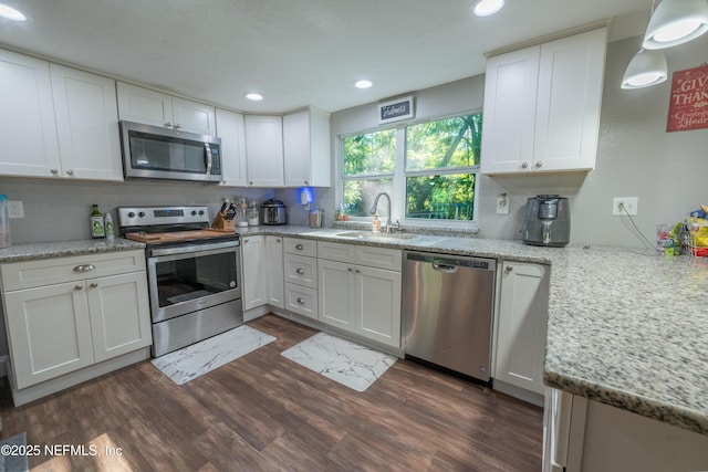 kitchen with appliances with stainless steel finishes, a sink, dark wood finished floors, and white cabinets
