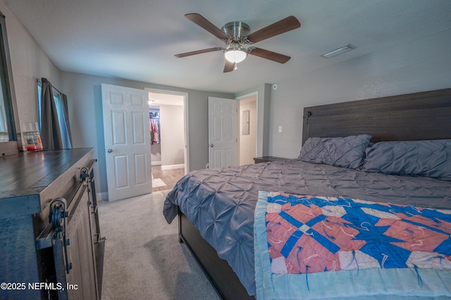 carpeted bedroom with ceiling fan, baseboards, ensuite bathroom, and visible vents