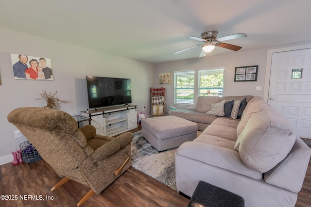 living room with dark wood-type flooring, baseboards, and ceiling fan