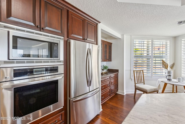 210 N Serenata Dr Unit 521, Ponte Vedra Beach, FL 32082 - kitchen featuring a textured ceiling, visible vents, dark wood finished floors, baseboards, and stainless steel appliances