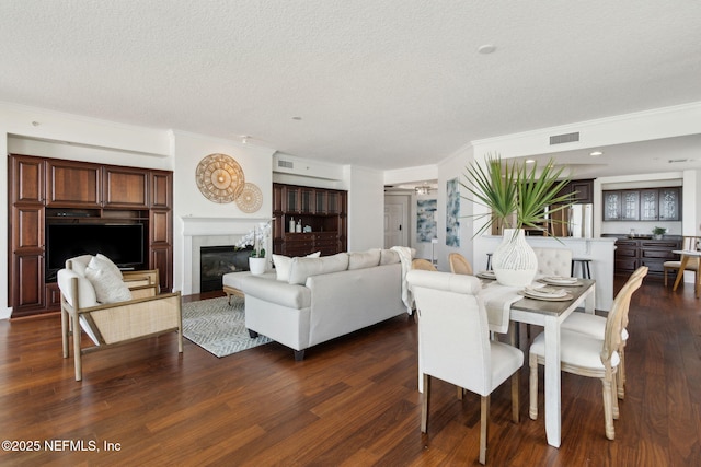 210 N Serenata Dr Unit 521, Ponte Vedra Beach, FL 32082 - dining space featuring visible vents, ornamental molding, dark wood-style flooring, a glass covered fireplace, and a textured ceiling