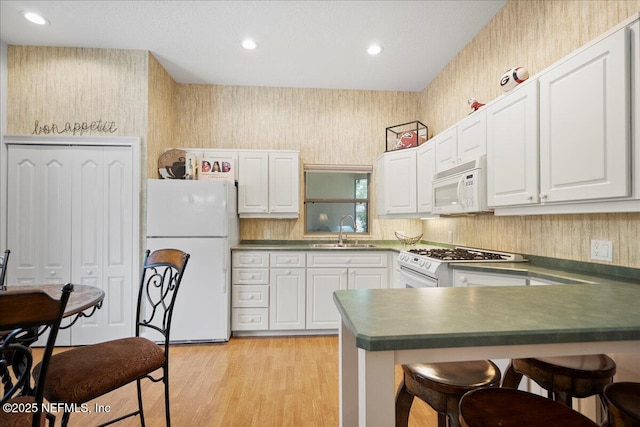 15 Dartmouth Trce, Ormond Beach, FL 32174 - kitchen with a sink, a kitchen breakfast bar, a peninsula, white appliances, and dark countertops