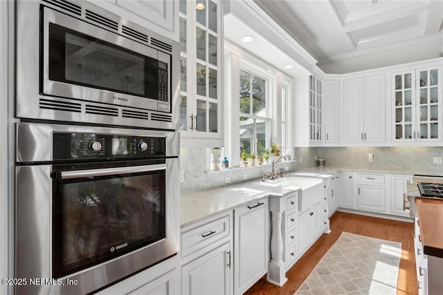 kitchen with a sink, ornamental molding, white cabinets, and appliances with stainless steel finishes