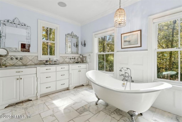 bathroom with double vanity, a soaking tub, crown molding, a wainscoted wall, and marble finish floor