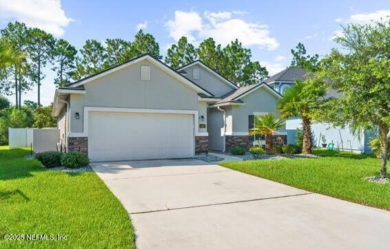 view of front of house with driveway, stone siding, a garage, and a front lawn