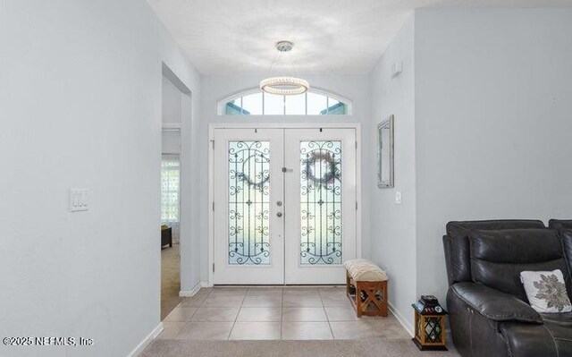 foyer featuring french doors, an inviting chandelier, baseboards, and tile patterned flooring