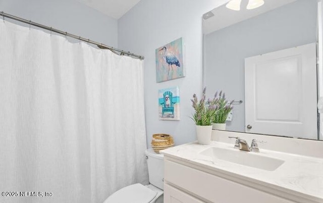 bathroom featuring toilet, a shower with shower curtain, and vanity