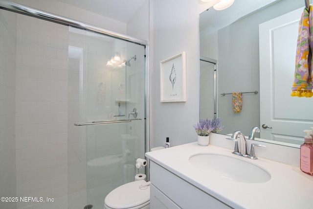 full bathroom featuring vanity, a shower stall, and toilet