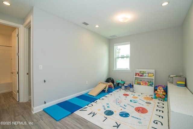 rec room with baseboards, recessed lighting, wood finished floors, and visible vents