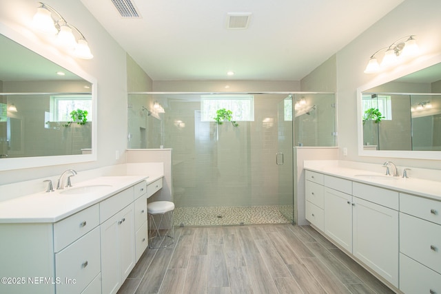 bathroom featuring visible vents, a sink, and a stall shower