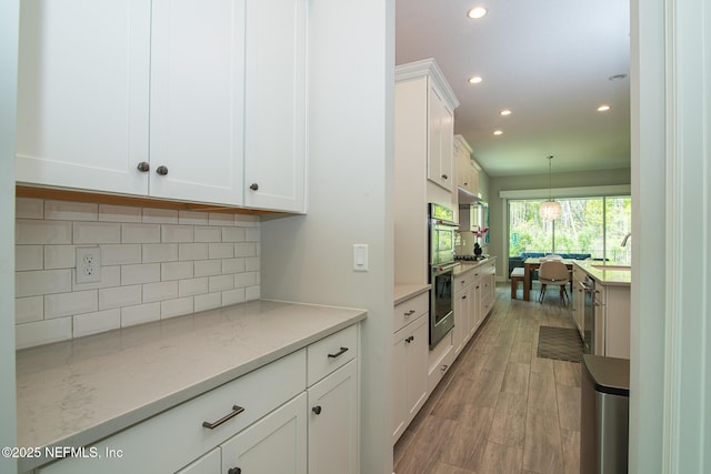kitchen with white cabinets, recessed lighting, backsplash, and light wood-style floors