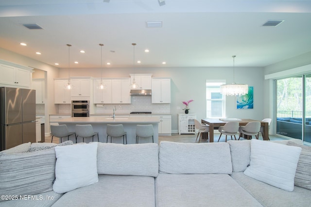 living area with a healthy amount of sunlight, a notable chandelier, and visible vents