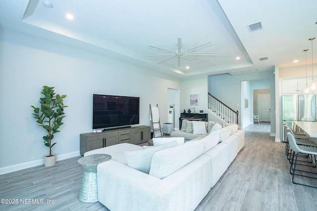 living room featuring a ceiling fan, visible vents, a tray ceiling, recessed lighting, and light wood-style flooring