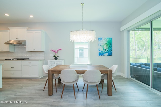 dining area with recessed lighting, a notable chandelier, a wealth of natural light, and light wood finished floors