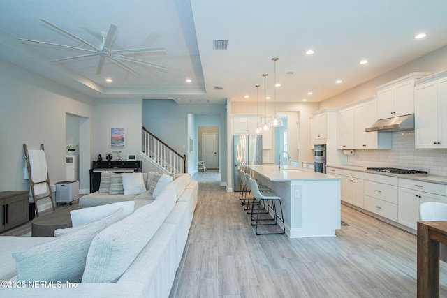 kitchen with appliances with stainless steel finishes, recessed lighting, open floor plan, under cabinet range hood, and visible vents