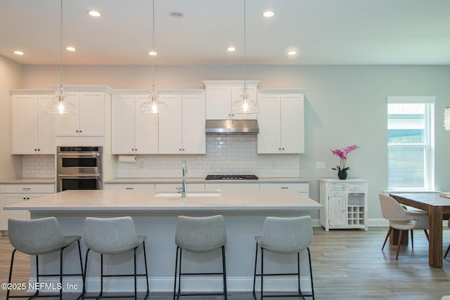 kitchen featuring a sink, light countertops, stainless steel double oven, and gas stovetop