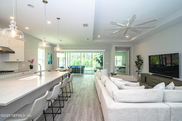 living room featuring recessed lighting, a ceiling fan, plenty of natural light, and light wood-style floors