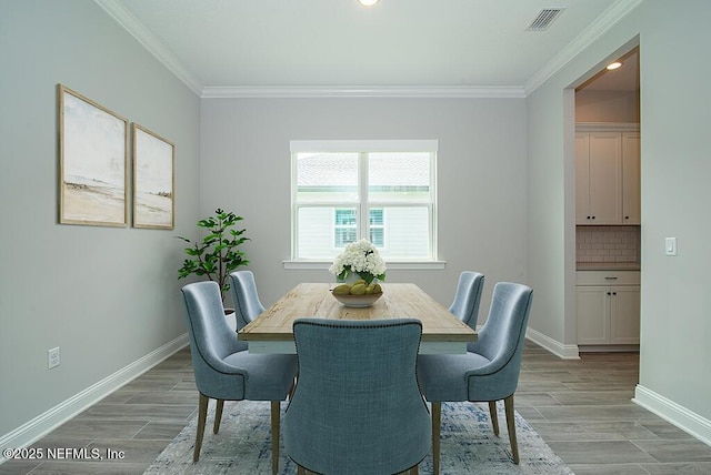 dining room with baseboards, ornamental molding, light wood finished floors, and visible vents