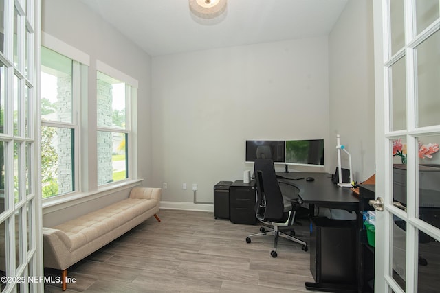 home office featuring plenty of natural light, baseboards, wood finished floors, and french doors