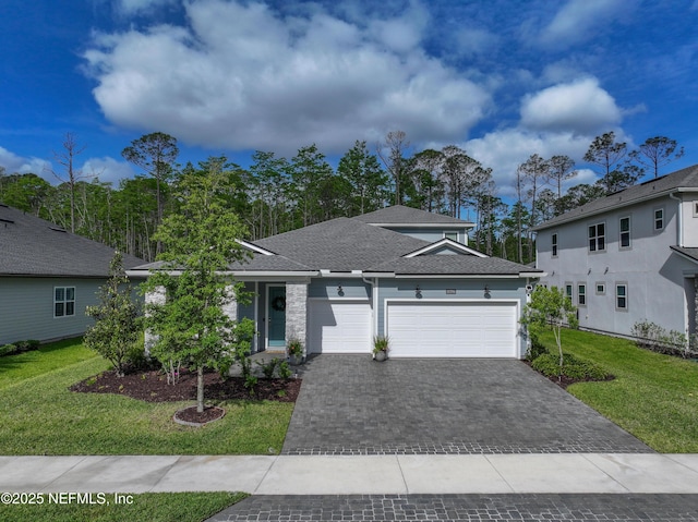 single story home featuring decorative driveway, a shingled roof, a front yard, and a garage