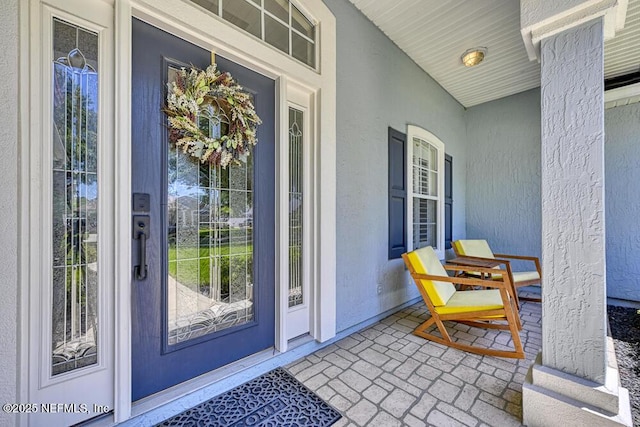 property entrance with a porch and stucco siding