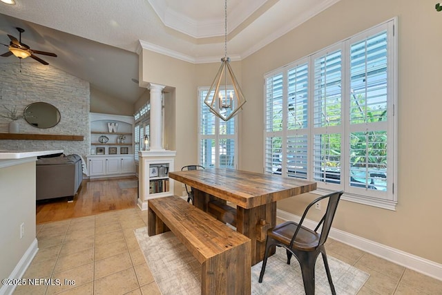 dining area featuring ceiling fan with notable chandelier, light tile patterned floors, a fireplace, baseboards, and ornate columns