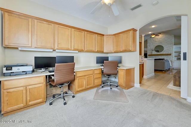 home office with visible vents, light carpet, built in desk, and ceiling fan