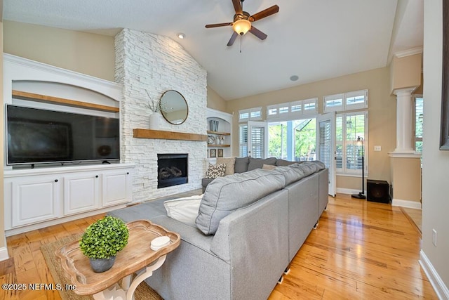 living area with a ceiling fan, light wood-style floors, built in shelves, a fireplace, and baseboards
