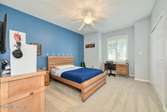 bedroom featuring ceiling fan, light carpet, a closet, and baseboards