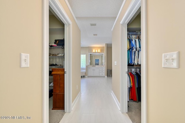 corridor with baseboards, a sink, visible vents, and light tile patterned floors