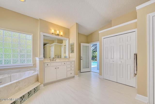 full bathroom with baseboards, a bath, a wealth of natural light, and vanity