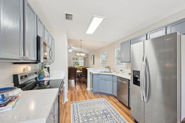 2734 Indigo Hills Ct, Jacksonville, FL 32221 - kitchen featuring a sink, light wood-type flooring, a chandelier, lofted ceiling, and appliances with stainless steel finishes