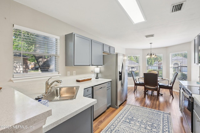 2734 Indigo Hills Ct, Jacksonville, FL 32221 - kitchen featuring stainless steel appliances, light countertops, visible vents, a sink, and light wood-type flooring