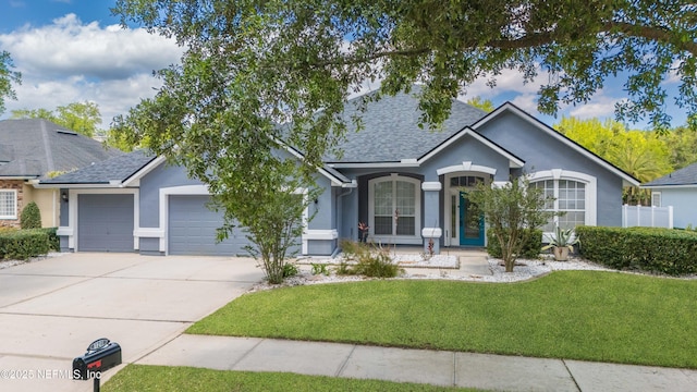 120 Oakwood Plantation Dr, Fleming Island, FL 32003 - ranch-style home featuring concrete driveway, roof with shingles, stucco siding, an attached garage, and a front lawn