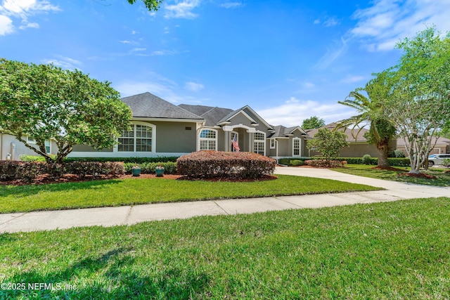view of front facade featuring stucco siding, a front lawn, and driveway