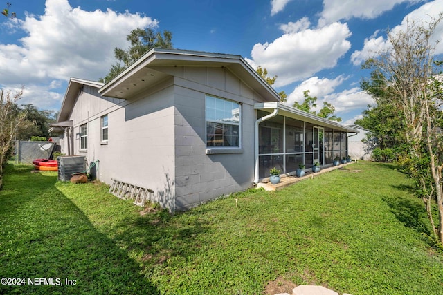 7876 Spanish Oaks Dr, Jacksonville, FL 32221 - view of home's exterior with a sunroom, central AC, a lawn, and concrete block siding